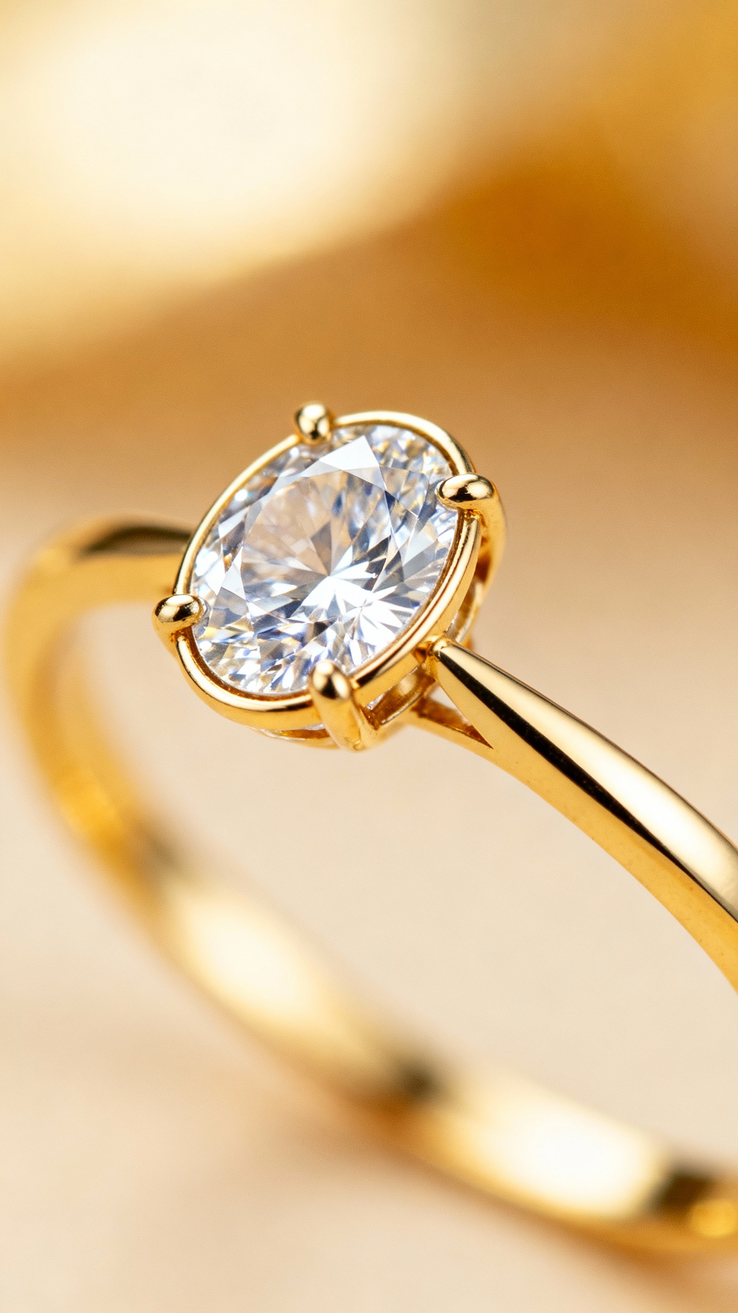 Closeup bezel-set oval diamond on thin yellow gold knife-edge band