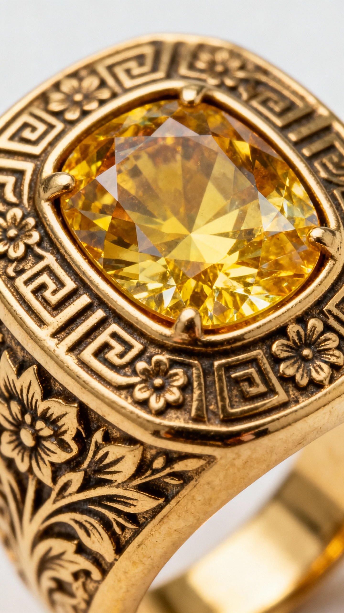 Closeup gypsy-set yellow diamond in chunky engraved signet-style gold ring
